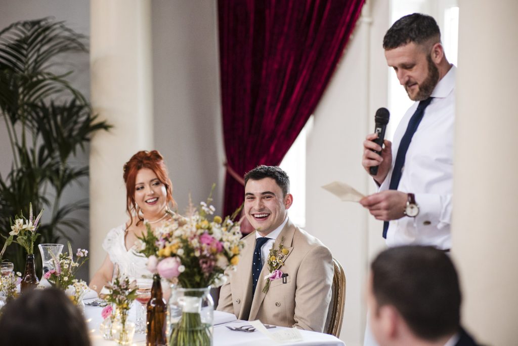 The best man giving a speech on the wedding day and the groom looking worried.