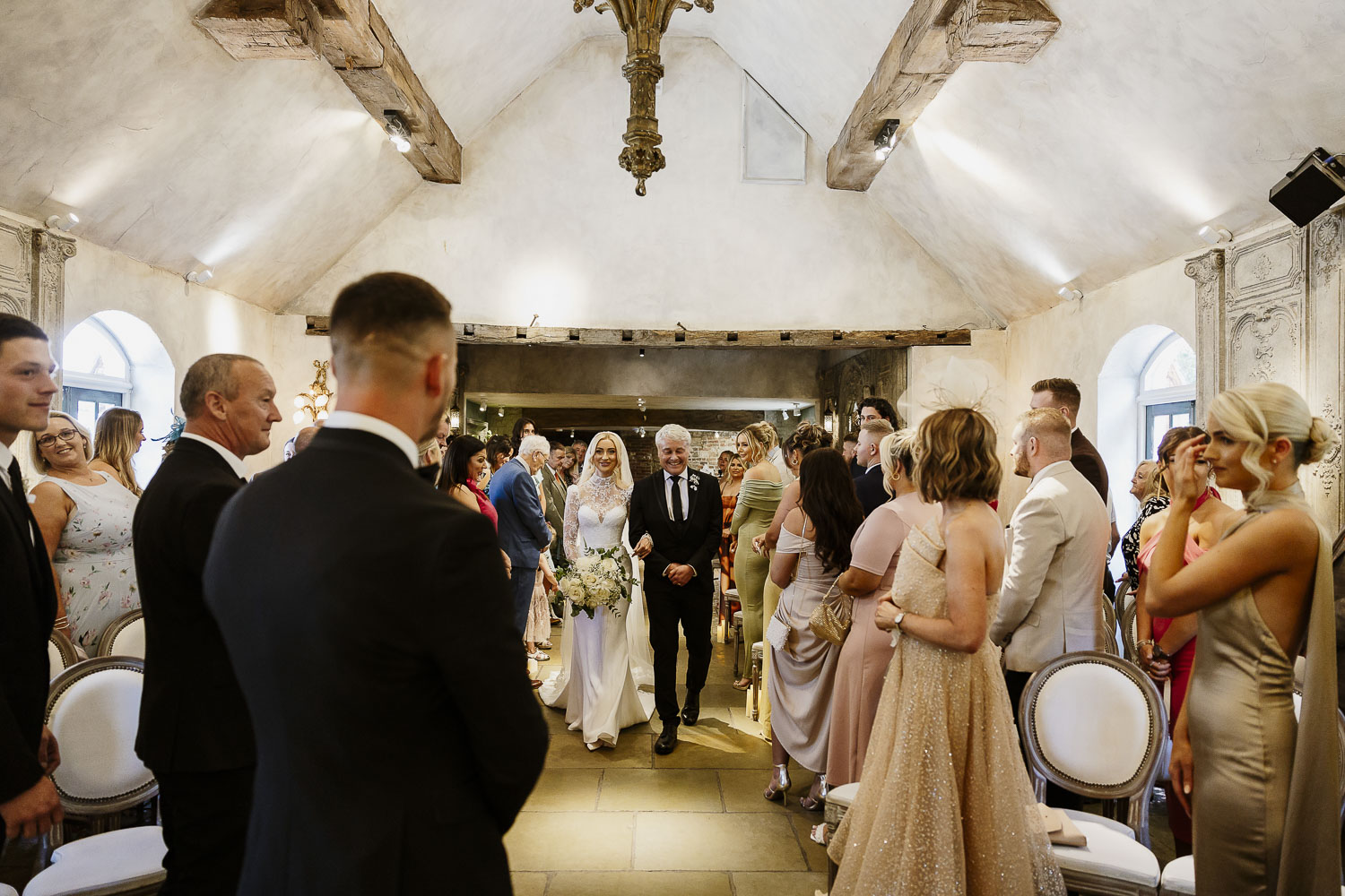 Bride coming down the aisle to get married to the groom at Le Petit Chateau. The wedding was in the rustic barn.
