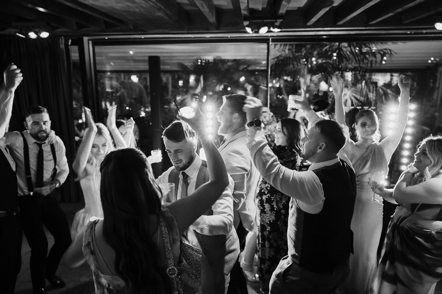 Wedding guests dancing on the dance floor with a DJ playing music with his disco lights on.