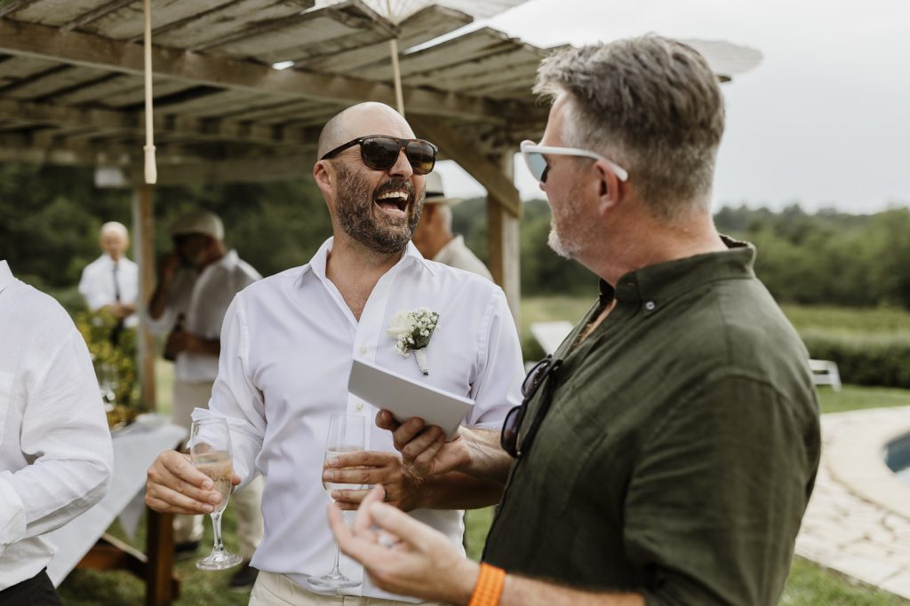 Groom having a laugh with another wedding guest.