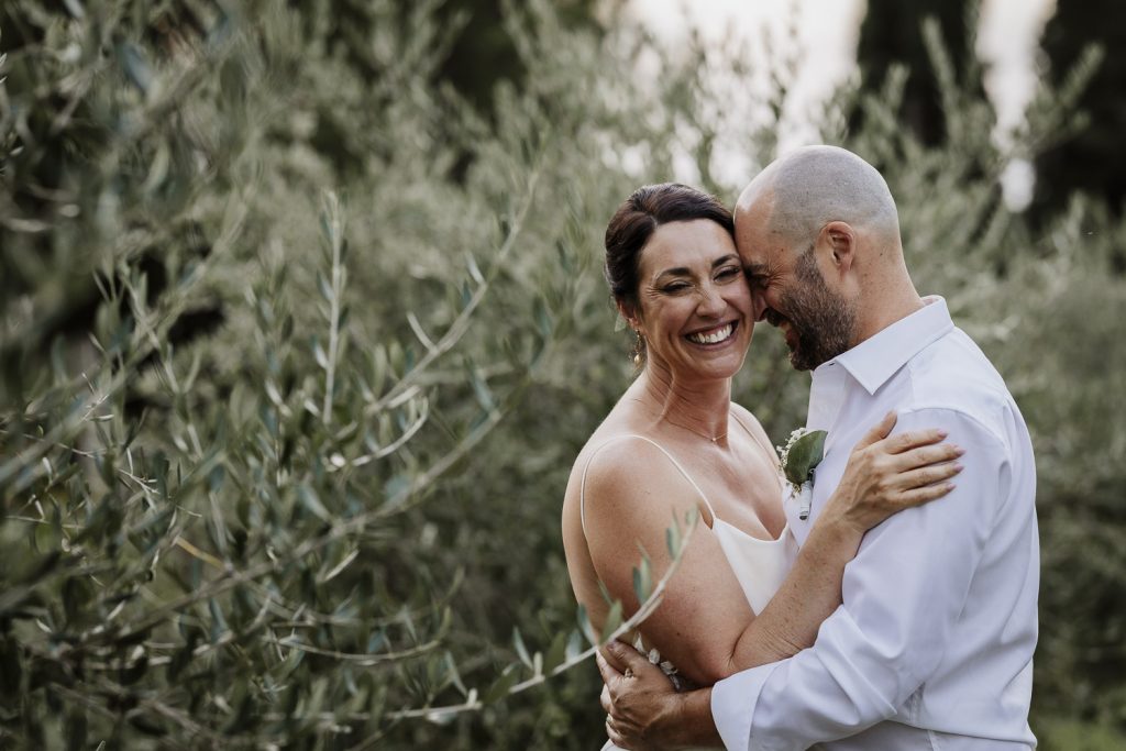 Bride and groom embracing in the olive groves at sunset.
