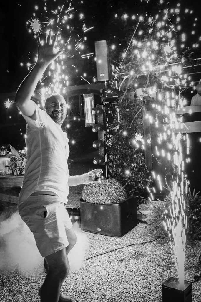 Groom dancing in front of outdoor sparklers on his wedding day.