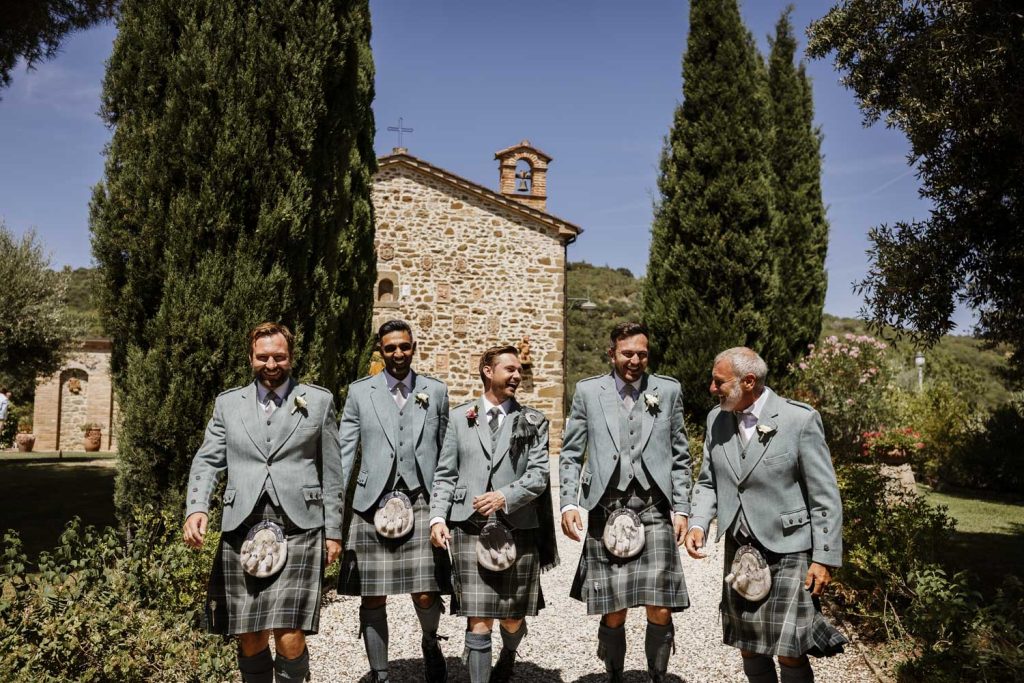 The groom and groomsmen walking down the driveway at Villa San Crispolto. The groom is wearing a kilt on his wedding day.