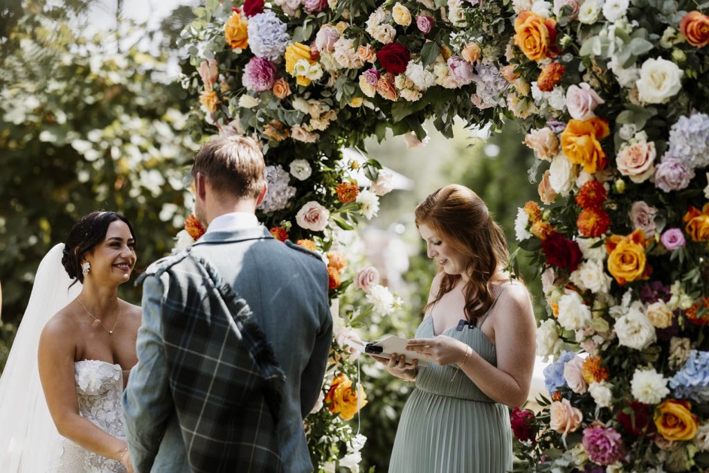 Bride and groom getting married at Villa San Crispolto in front of a stunning flower arch.