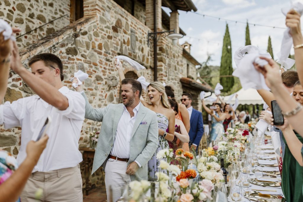 Guests waving their napkins as the wedding couple walk in to sit at the dinner table.