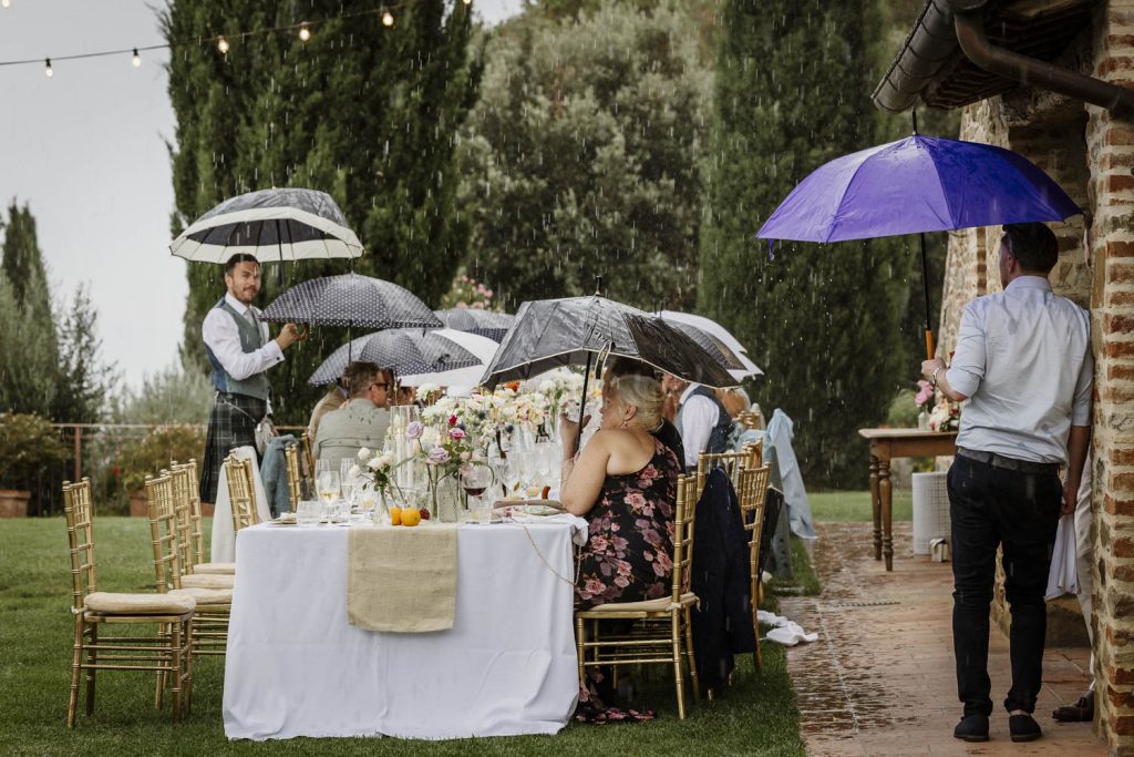 It started to rain during the wedding meal so people hiding under umbrellas at Villa San Crispolto.