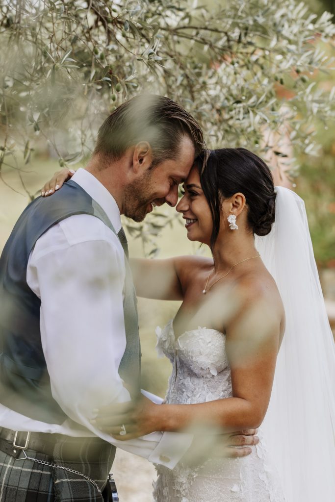 Bride and groom embracing at sunset under the olive groves at Villa San Crispolto.