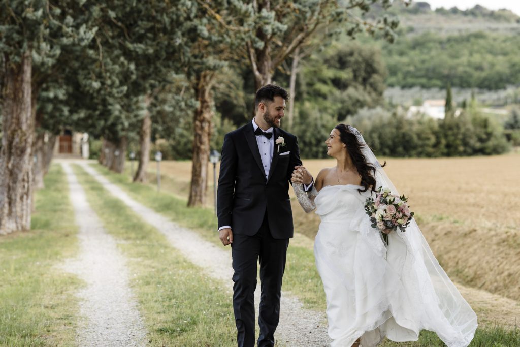 Bride and groom walking down a footpath at the front of the villa in Italy where they had their destination wedding