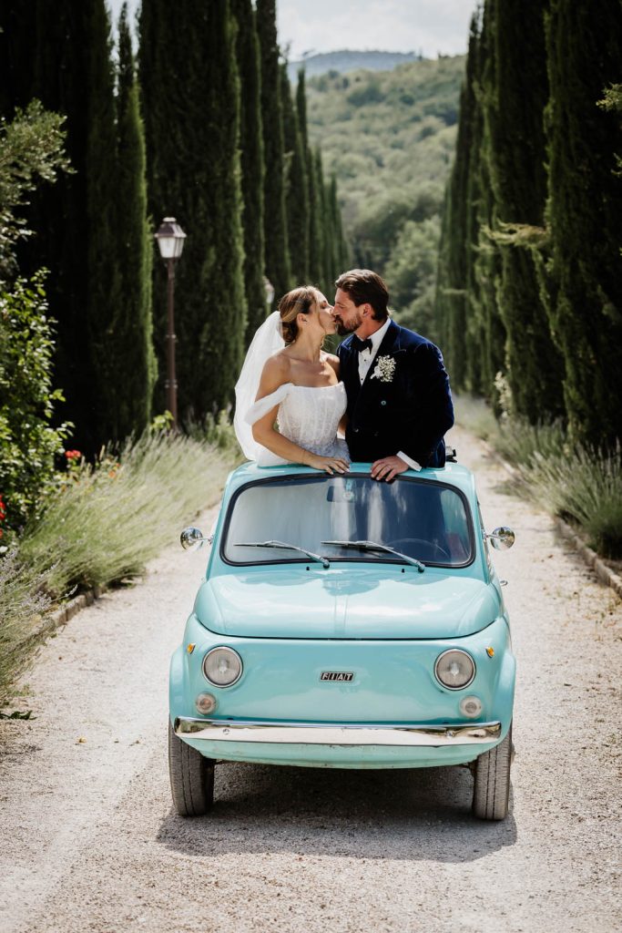 Bride and groom having a kiss in their Fiat 500 on the drive of Villa Baoncino