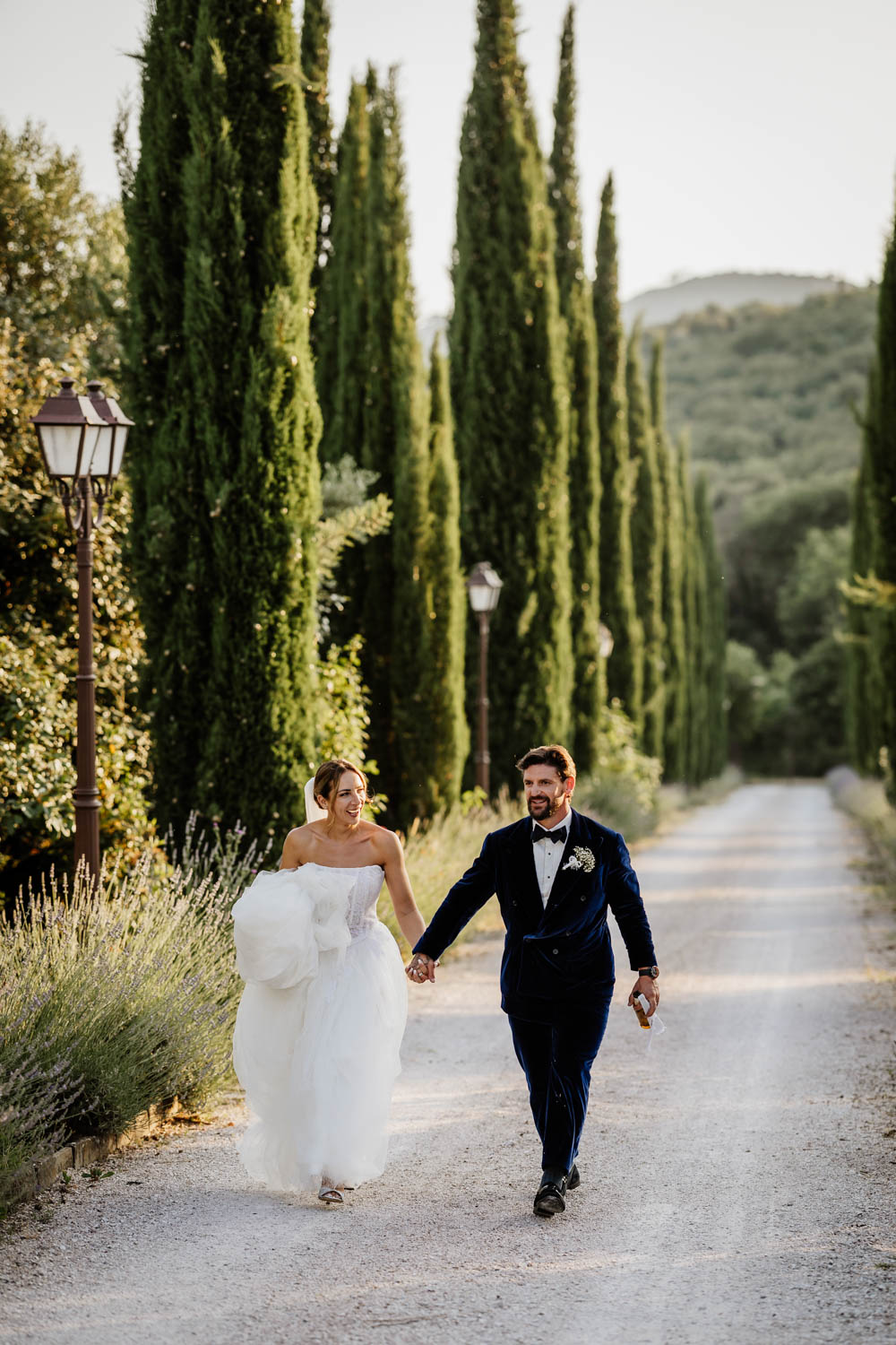Bride and groom walking up the drive of Villa Baroncino at sunset