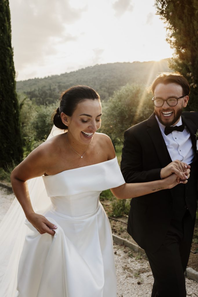 Bride and groom hand in hand on their wedding day laughing as they walk up the drive of Villa Baroncino on their destination wedding.