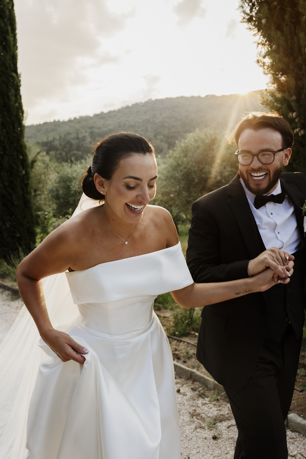 Bride and groom hand in hand on their wedding day laughing as they walk up the drive of Villa Baroncino on their destination wedding.