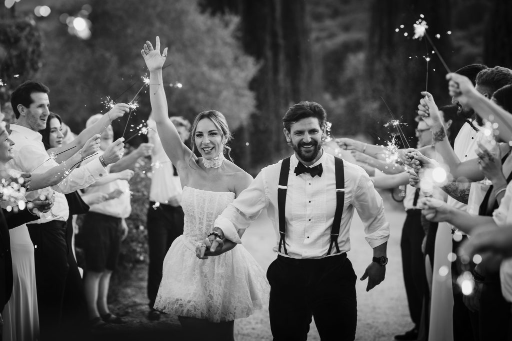 Bride and groom walking between guests who have sparklers on their wedding day at Villa Baroncino