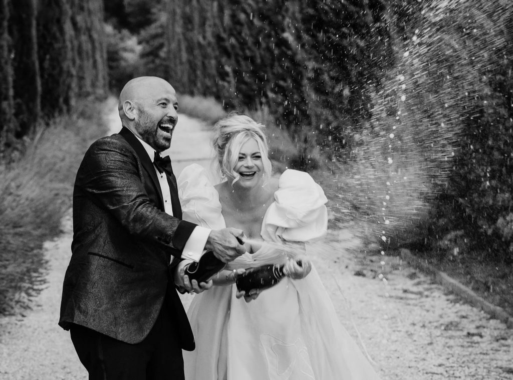 Bride and groom on their wedding at Villa Baroncino spraying champagne.