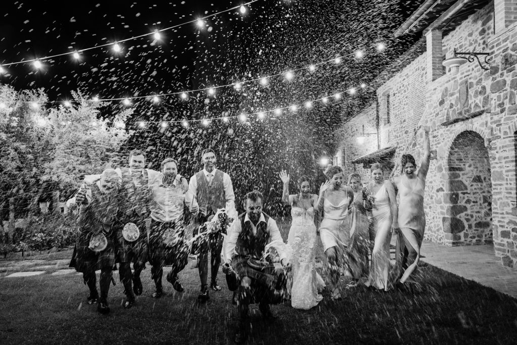 Bridal party shaking a bottle of champagne on their wedding day