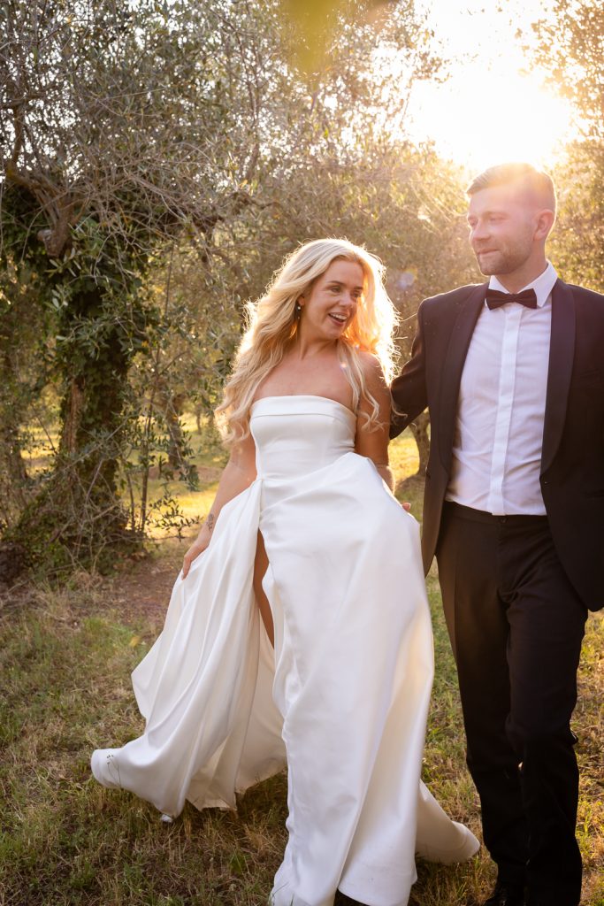 Bride and groom at Villa Baroncino on their wedding day walking hand in hand in the olive groves at sunset